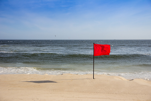 red flag at the beach, with kitesurfers in the background