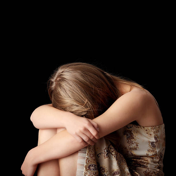 istock Young depressed woman slumped against black background 92358416