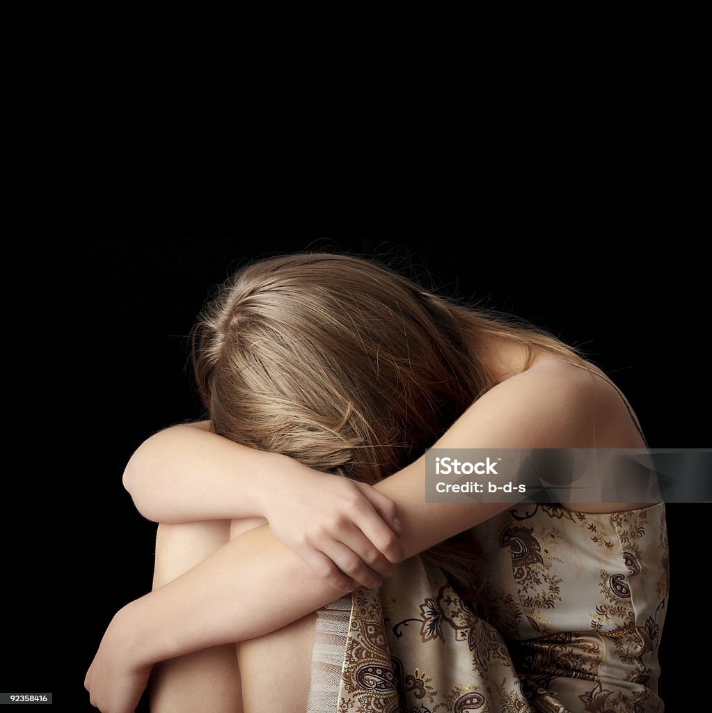 Young depressed woman slumped against black background Young woman depression isolated on black background Abandoned Stock Photo