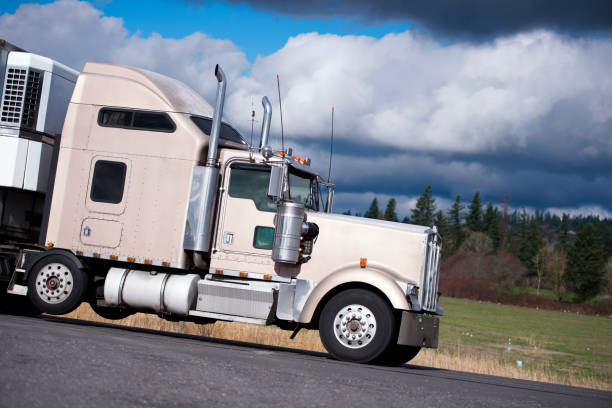 istock Big rig classic powerful semi truck with chrome accessories transporting cargo in refrigerator semi trailer on the road 923585348