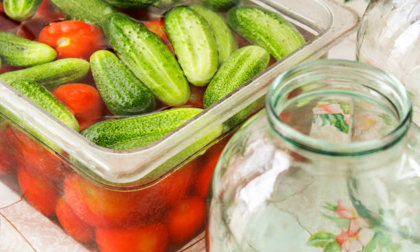 Canning fresh vegetables for the winter Preparation of pickles for the winter. Tomatoes and cucumbers in brine and glass jars on the table. beines stock pictures, royalty-free photos & images