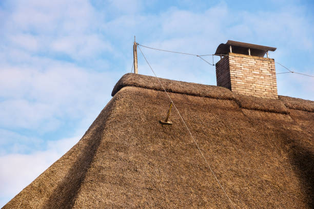 istock lightning rod on a thatched roof with a chimney against a blue sky with clouds, copy space 923594000