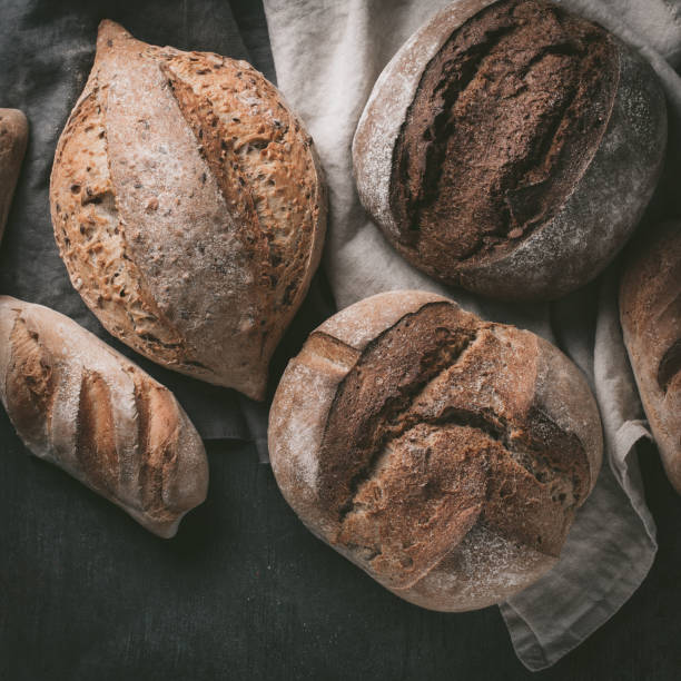 istock Flat-lay of various bread selection. Multigrain rustic bread on kitchen towels over grey background, top view, copy space 923594114