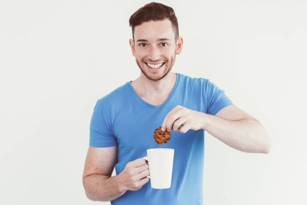 istock Happy man immersing cookie into warm beverage 923597526