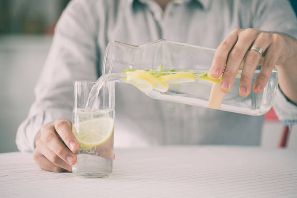 istock Young man pouring water from bottle to water in kitchen 923598328