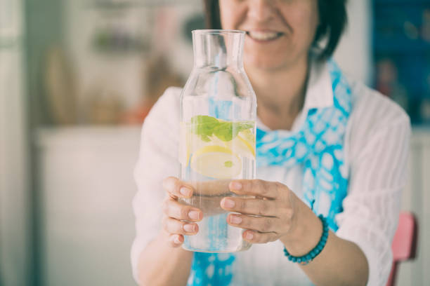 istock Woman holding  bottle with water lemon and mint in kitchen 923598734