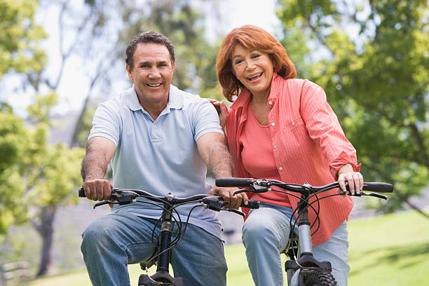 casal equitação bicicletas - senior adult action cycling senior couple imagens e fotografias de stock