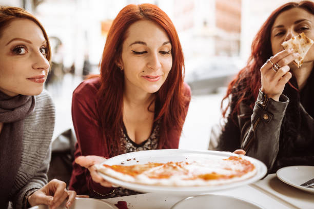 istock woman eating pizza in italy 923598982