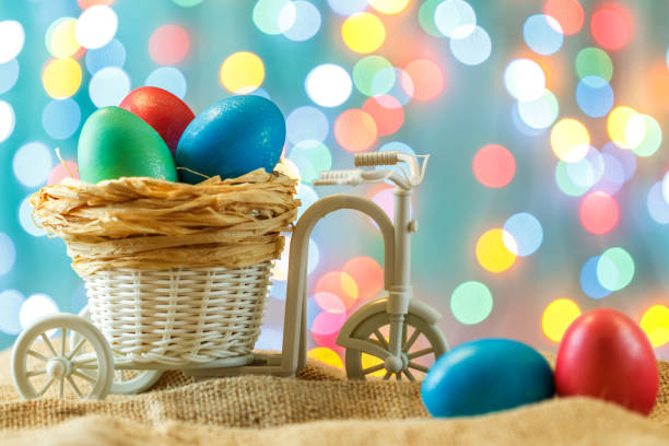 easter card, colored eggs in the nest. toy bicycle with a cart. happy easter. delicate blue background. place for text. - bicycle isolated basket red imagens e fotografias de stock
