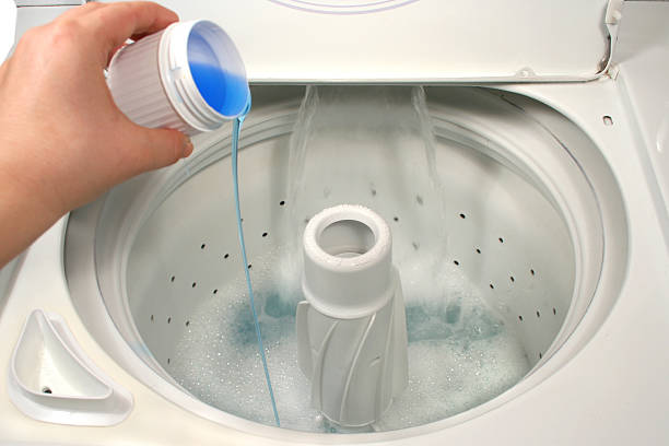 istock Hand pouring blue liquid into washing machine 92360317