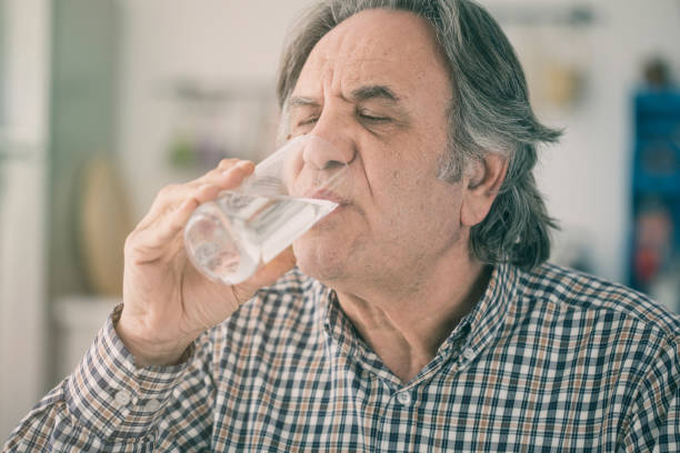 istock Senior man drinking water from glass in kitchen 923605138