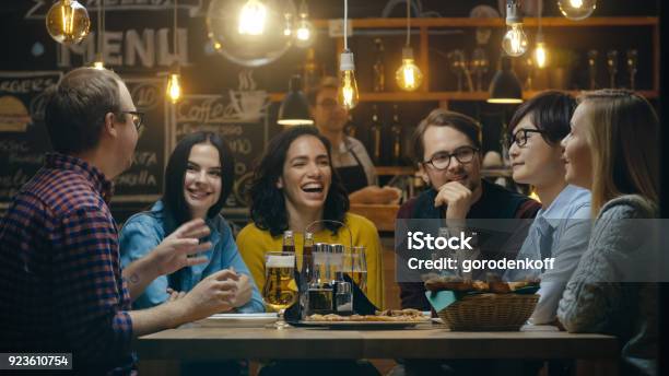 Diverse Group Of Young People Have Fun In Bar Talking Telling Stories And Jokes They Drink Various Drinks Theyre In The Stylish Hipster Establishment Stock Photo - Download Image Now