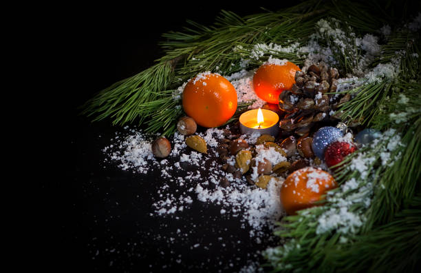 pino de ramas, velas, adornos de árbol, mandarinas, tuercas, el cono de pino en la nieve sobre un fondo negro - pine nut tree pine tree pine cone fotografías e imágenes de stock