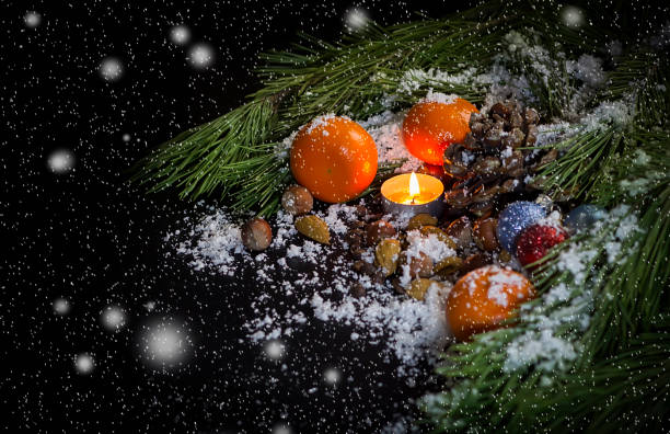 pin de branches, bougies, décorations pour arbres de noël, mandarines, noix, le cône de pin dans la neige sur un fond noir - pine nut tree pine tree pine cone photos et images de collection