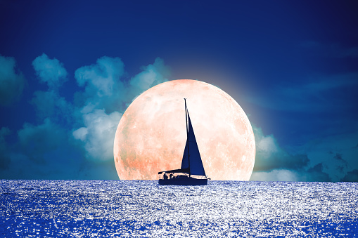Silhouette of a boat with full Moon on the ocean. My astronomy work.