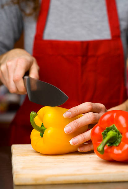 Woman cutting fresh bell peppers stock photo