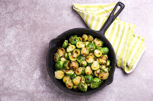Vegetarian cuisine. Homemade Brussels Sprouts roasted with olive oil on gray slate background. Copyspace, top view, flatlay.