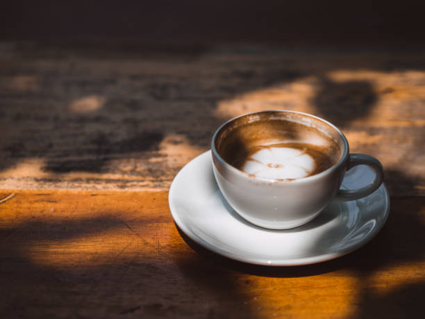 istock White hot cup of Latte coffee on wooden table in shadow shade. 923623616