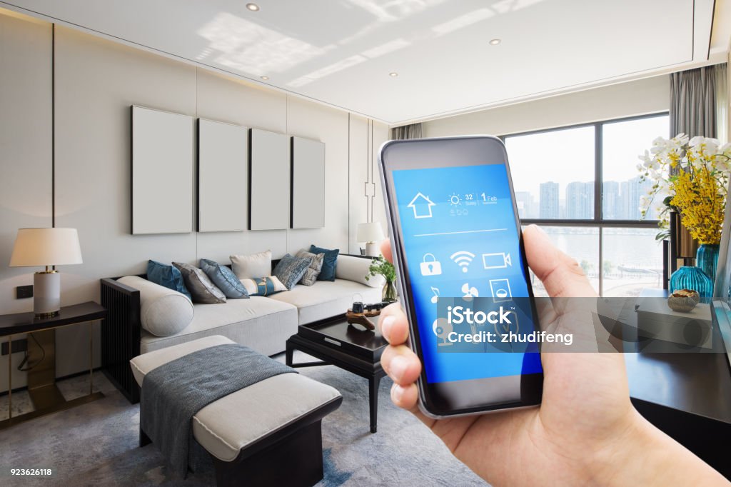 smart home system on mobile phone with background smart home system on mobile phone with background of modern living room Home Automation Stock Photo