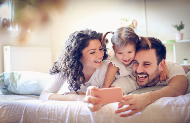 facciamo una foto della nostra famiglia felice. - bed child smiling people foto e immagini stock