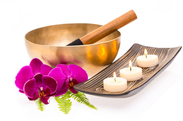 Singing bowl with fern, orchid and candles isolated on white background stock photo