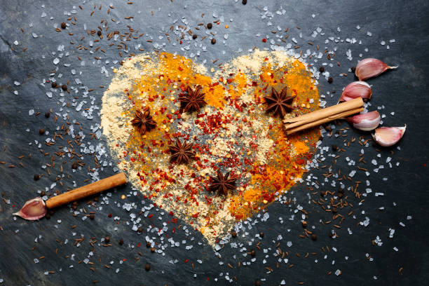 Heart shape made from spices with cinnamon and garlic arrow on slate background