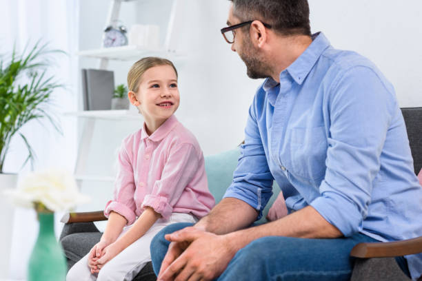 istock father in eyeglasses and daughter looking at each other while sitting on sofa at home 923634508