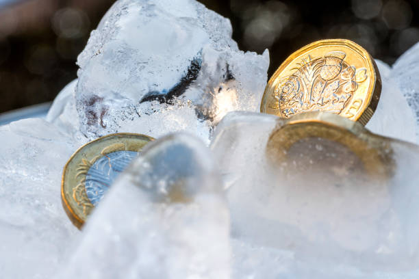 замороженные новые британские один фунт стерлингов монета близко макро внутри кубиков льда - frozen currency finance ice стоковые фото и изображения