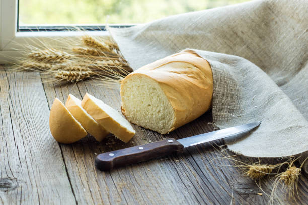 istock Sliced bread with wheat spikes on wooden table closeup 923648432