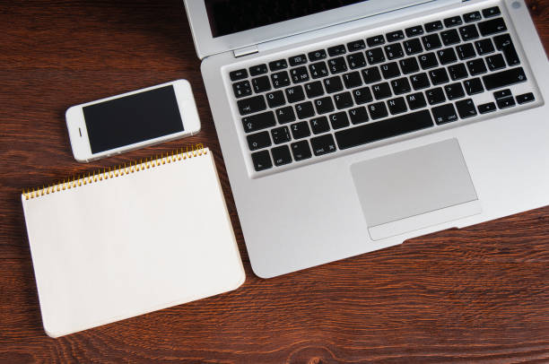 istock Notepad, laptop and mobile phone on wood table 923652560