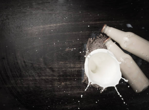 istock Milk splash and bottle milk on dark wooden table,Top view 923652682