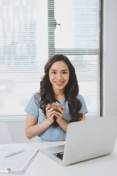 istock Asian woman working at office drinking coffee smiling at desk 923660830
