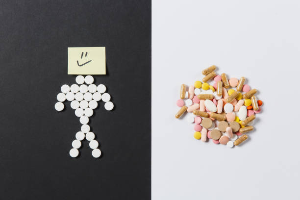 istock Medication white colorful round tablets arranged abstract on white black background. Human smile, aspirin, capsule pills design. Treatment choice healthy lifestyle concept. Copy space advertisement. 923663586