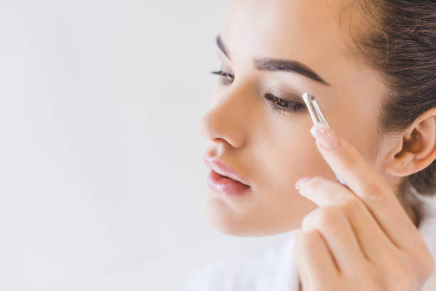 istock young woman plucking eyebrows with tweezers 923666704