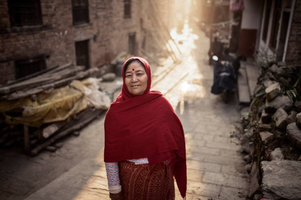 Aged women standing at the street with back light.
