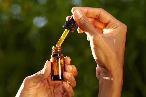 a dropper containing CBD oil in a woman's hand