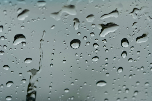 photo of irregularly shaped water droplets with various shapes on a black surface. lots of water drops on a plastic background