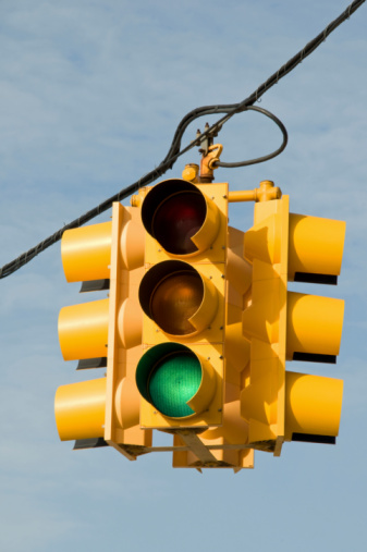 Red traffic signal with sky and clouds background in Brazil.