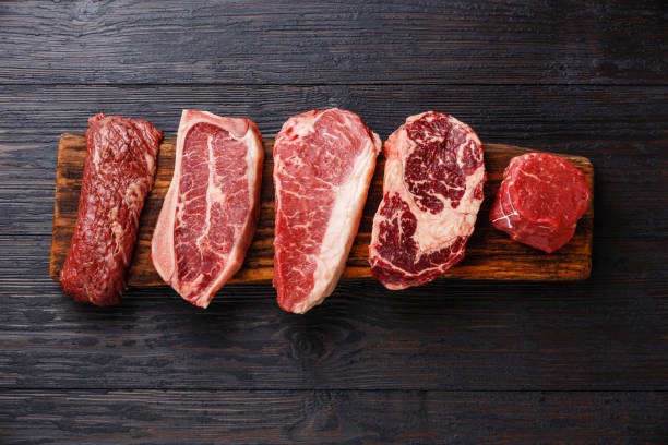 Variety of Raw Black Angus Prime meat steaks Variety of Raw Black Angus Prime meat steaks Machete, Blade on bone, Striploin, Rib eye, Tenderloin fillet mignon on wooden board copy space raw food stock pictures, royalty-free photos & images