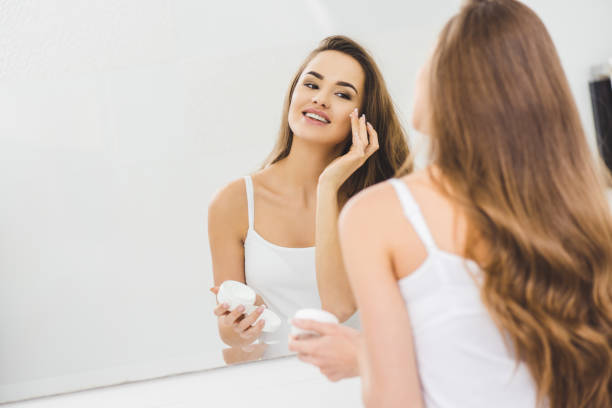 istock mirror reflection of beautiful woman applying face cream 923692730