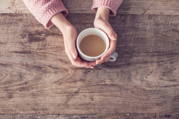 istock Woman holding coffee cup wooden background 923692744