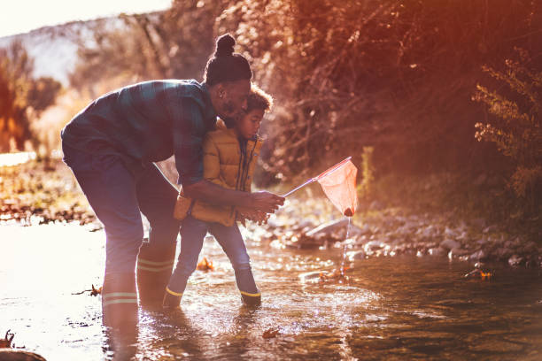 istock Father teaching son how to fish in mountain stream river 923693414