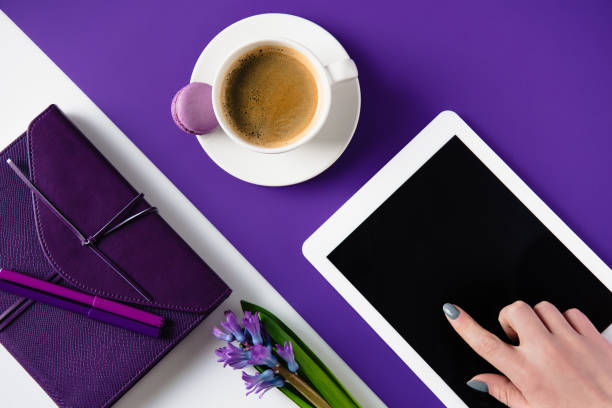 cropped image of woman using tablet at white and purple table