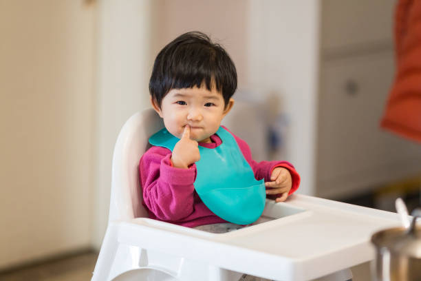 Cute baby Sitting in a high chair waiting for to eat dinner stock photo