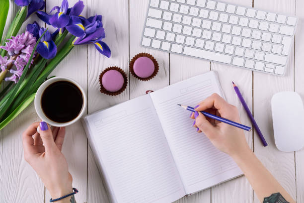 cropped shot of woman writing in notebook at workplace