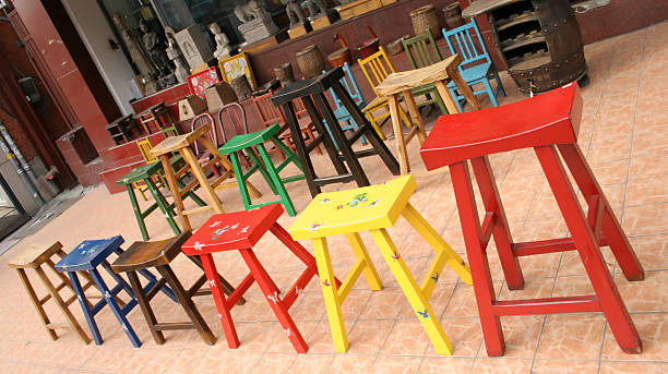 A vibrant selection of colorful balcony chairs organized in a neat row at a bustling shopping mall. The image highlights the variety of styles and hues, perfect for enhancing any outdoor space with a touch of personality and comfort. Ideal for themes related to home decor, shopping experiences, and lifestyle choices, emphasizing the blend of aesthetic appeal and functionality in outdoor furniture.