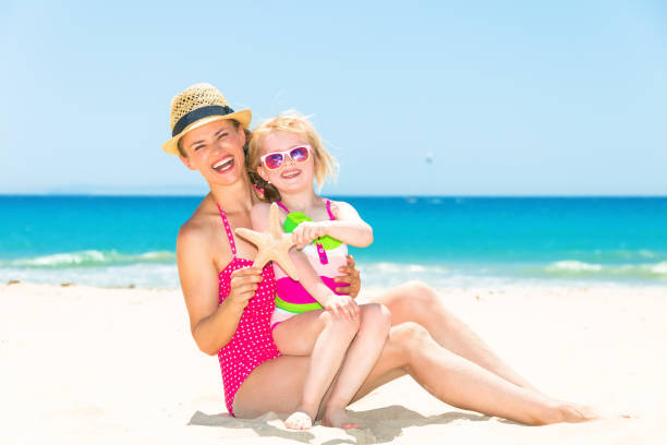 istock smiling young mother and child on beach showing starfish 923718142