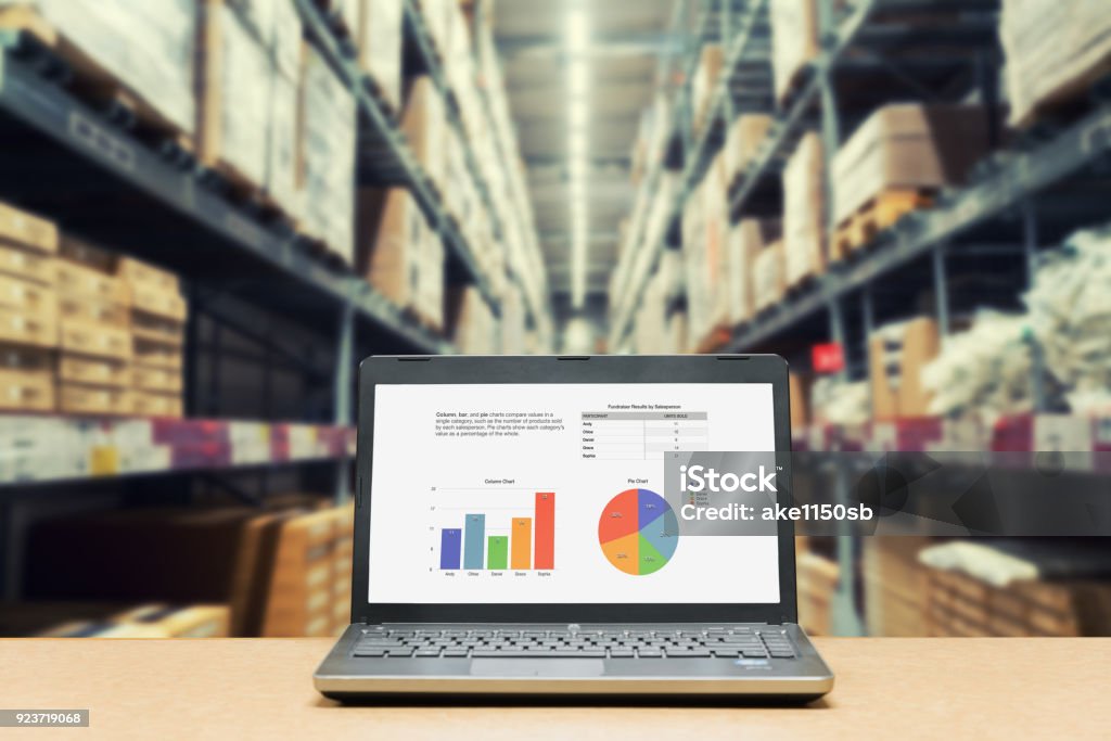 Laptop with analysis sale screen on table with blur warehouse cargo in factory. Smart factory concept. Freight Transportation Stock Photo