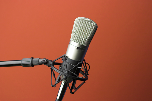 Professional microphone and anti vibration on mic stand. Microphone in sound studio production. Close up microphone and Shock mount pop filter at studio. Condenser mic against dark and copy space.