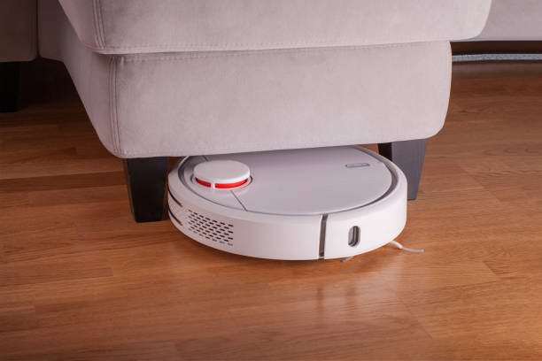 istock Robot vacuum cleaner runs under sofa in room 923737528